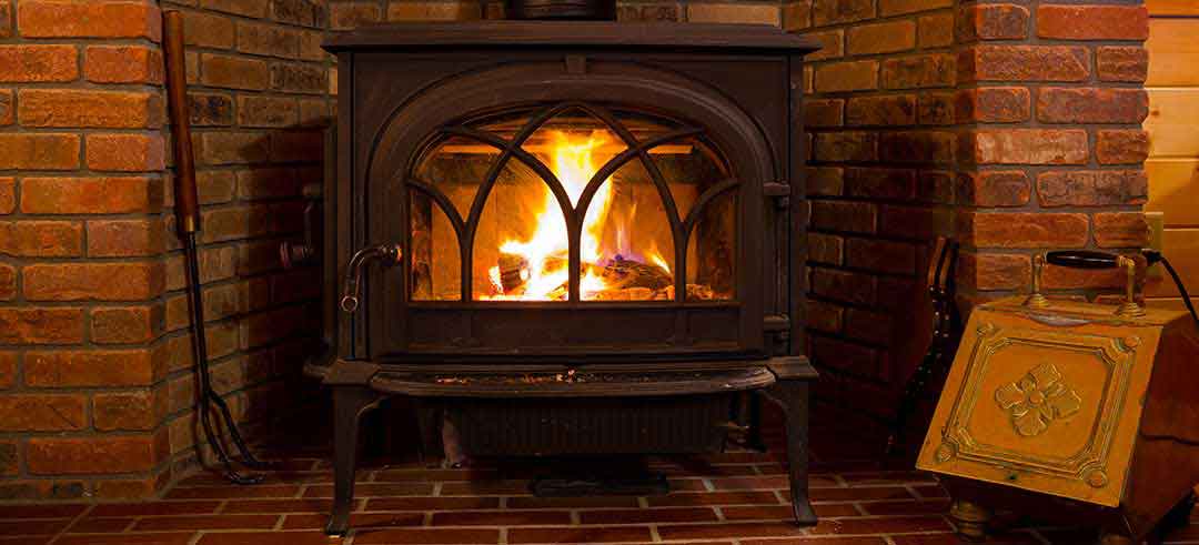 Beautiful freestanding stove with elaborate door tools to the left with brick surround - Nor